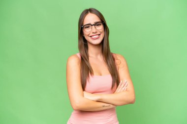 Genç, beyaz, soyutlanmış, kollarını kavuşturup ileriye bakan bir kadın.