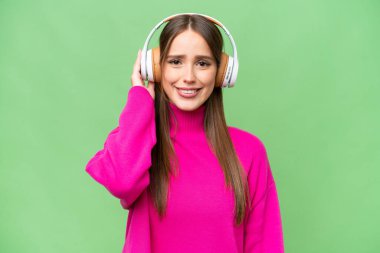 Genç, güzel, beyaz bir kadın izole edilmiş arka planda müzik dinliyor.