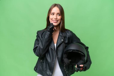 Motosiklet kaskı takmış genç, beyaz bir kadın izole bir arka planda yukarı bakarken bir fikir düşünüyor.