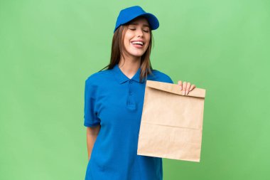 Young beautiful caucasian woman taking a bag of takeaway food over isolated background laughing