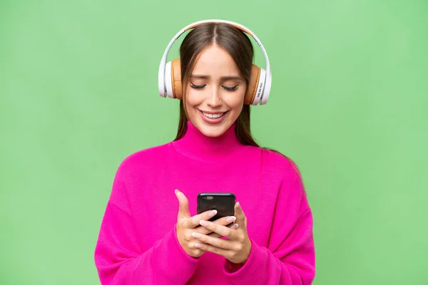 Giovane Bella Donna Caucasica Sfondo Isolato Ascoltare Musica Cercando Cellulare — Foto Stock