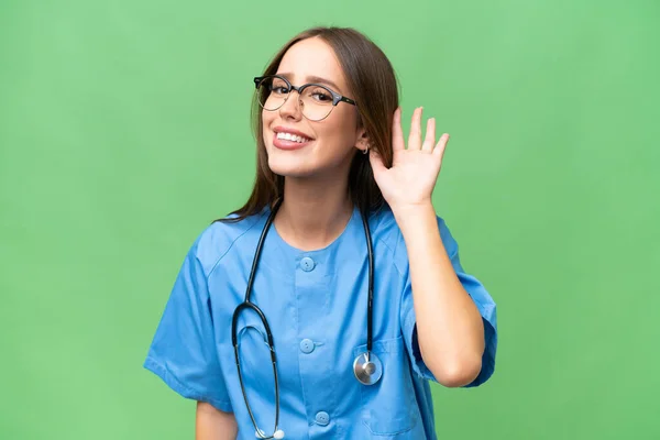 stock image Young nurse caucasian woman over isolated background listening to something by putting hand on the ear