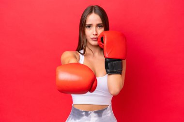 Kızıl arka planda boks eldivenleriyle izole edilmiş güzel beyaz bir kadın.