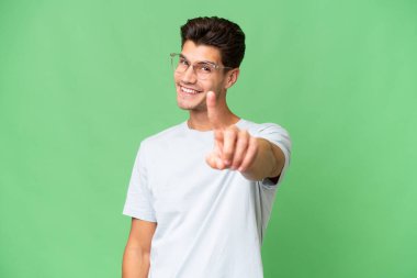 İzole edilmiş geçmişi olan beyaz, yakışıklı bir adam parmağını kaldırıyor ve gösteriyor.