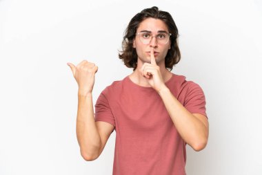 Beyaz arka planda izole edilmiş genç yakışıklı bir adam yan tarafı işaret ediyor ve sessiz hareketler yapıyor.