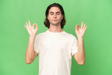 Zen pozisyonunda yeşil krom arka planda izole genç beyaz adam