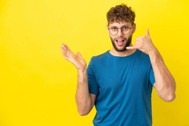 Sarı arka planda izole edilmiş yakışıklı beyaz bir adam telefon hareketlerinde bulunuyor.