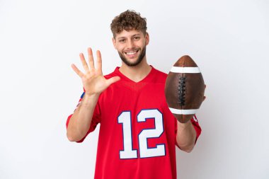 Beyaz arka planda ragbi oynayan beyaz tenli genç adam parmaklarıyla beşe kadar sayıyor.