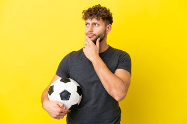 Yakışıklı genç futbolcu sarı arka planda izole edilmiş şüpheleri var.