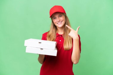 İş üniformalı beyaz pizza dağıtan kadın izole arka planda pizza kutularını topluyor ve baş parmak işareti yapıyor.
