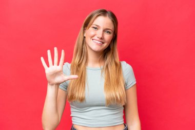 Kırmızı arka planda izole edilmiş genç ve güzel bir kadın parmaklarıyla beşi sayıyor