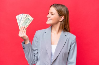 Kafkasyalı genç bir kadının elinde kırmızı arka planda izole edilmiş para var.