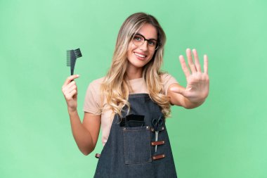 Genç Uruguaylı kuaför kadın izole arka planda beş parmaklı sayıyor.