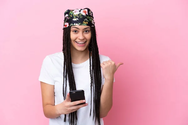 十代の女の子とともにBrids以上隔離されたピンクの背景使用して携帯電話と指すザ側面 — ストック写真