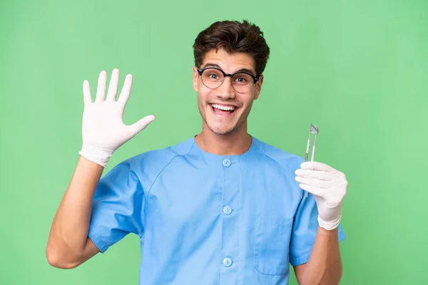 Jovem Dentista Homem Segurando Ferramentas Sobre Fundo Isolado Saudando Com — Fotografia de Stock
