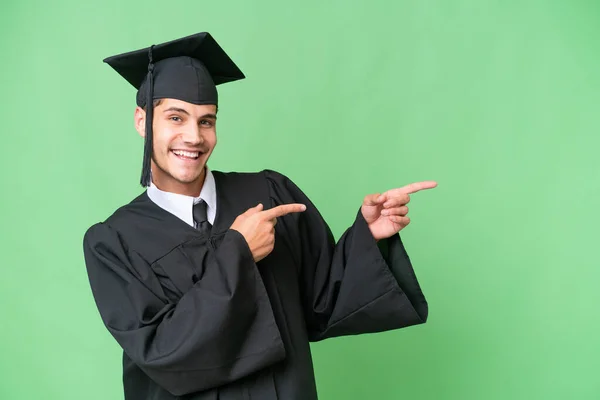 Młody Uniwersytet Absolwent Kaukaski Człowiek Odosobnionym Tle Wskazując Palcem Bok — Zdjęcie stockowe