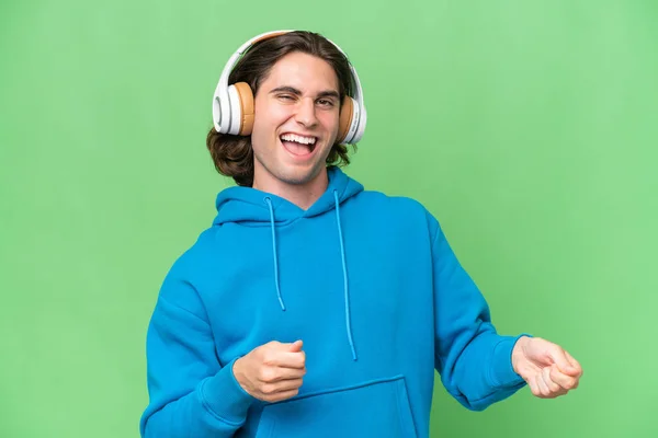 Jonge Knappe Man Geïsoleerd Groene Chroma Achtergrond Luisteren Muziek Doen — Stockfoto