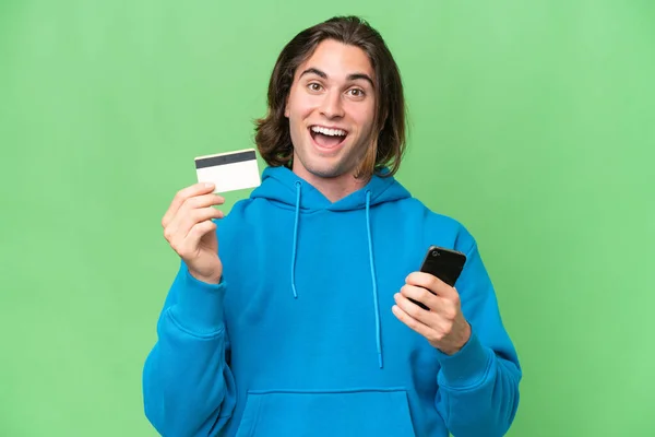 Mladý Pohledný Muž Izolovaný Zeleném Chroma Pozadí Nákup Mobilním Telefonem — Stock fotografie