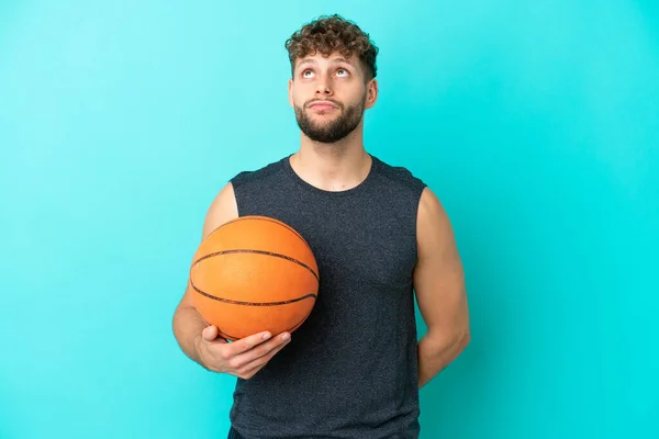 Pemuda Tampan Bermain Basket Terisolasi Latar Belakang Biru Dan Melihat — Stok Foto
