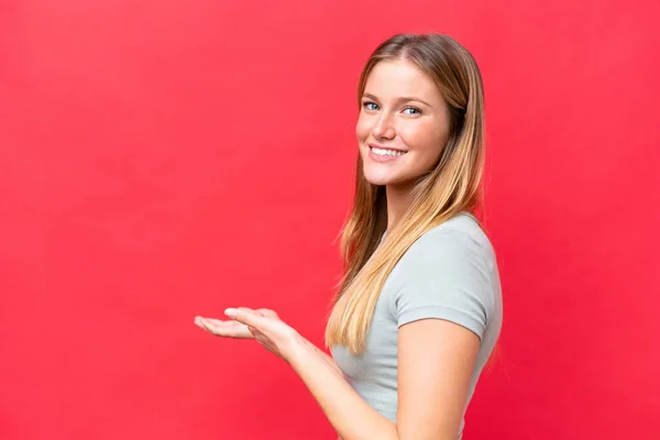 Young Beautiful Woman Isolated Red Background Extending Hands Side Inviting — Stockfoto