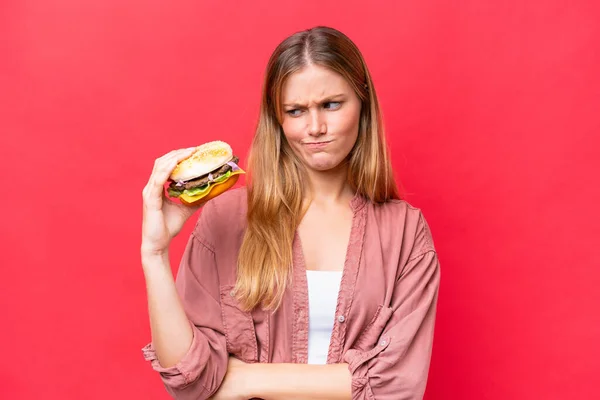 Jeune Femme Caucasienne Tenant Hamburger Isolé Sur Fond Rouge Avec — Photo