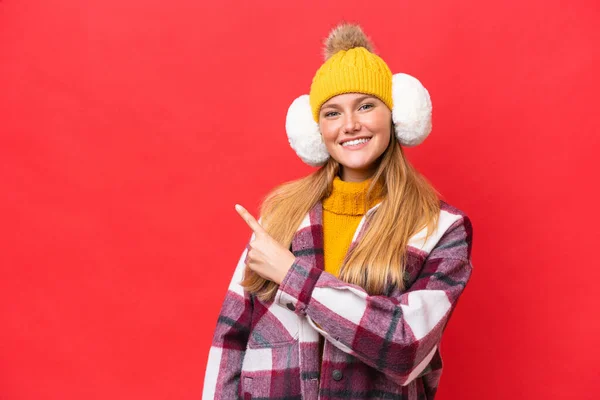 Νεαρή Όμορφη Γυναίκα Φορώντας Muffs Χειμώνα Απομονώνονται Κόκκινο Φόντο Που — Φωτογραφία Αρχείου