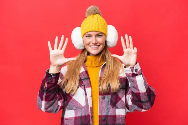 年轻美丽的女人穿着冬季的围巾 红色背景下被隔离 有9个手指 — 图库照片