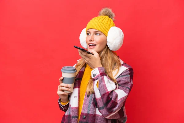 Junge Schöne Frau Wintermützen Isoliert Auf Rotem Hintergrund Hält Kaffee — Stockfoto