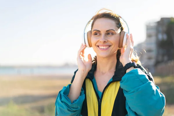 옥외에 여자가 스포츠용 헤드폰을 음악을 듣는다 — 스톡 사진