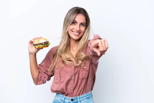 Młoda Ładna Urugwajska Kobieta Trzyma Hamburgera Odizolowanego Białym Tle Wskazuje — Zdjęcie stockowe