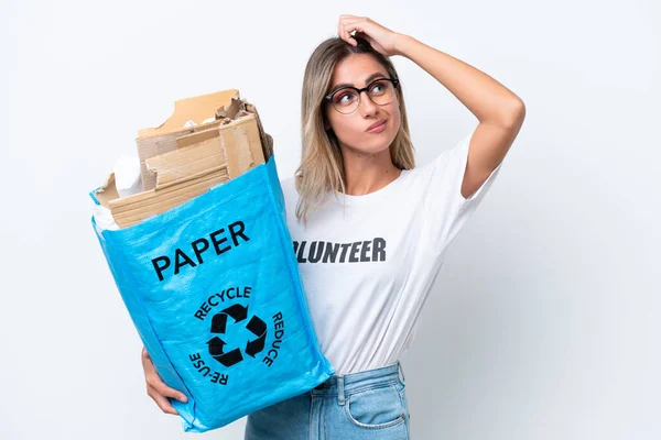 年轻而漂亮的乌拉圭女人拿着一个装满纸的回收袋 在白色背景下进行回收 满脸疑惑 表情混乱 — 图库照片