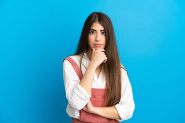 Kafkasyalı genç bir kadın mavi arka planda soyutlanmış düşünüyor.