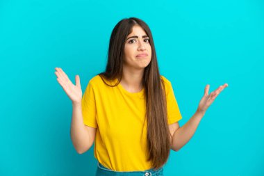 Mavi arka planda izole edilmiş genç beyaz kadın şüpheli hareketler yapıyor.