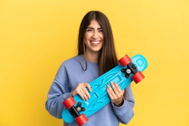 Sarı arka planda, mutlu bir ifadeyle paten kayan beyaz bir kadın.