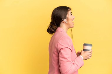 İş kadını beyaz tenli, sarı arka planda izole edilmiş. Yan pozisyonda gülüyor.