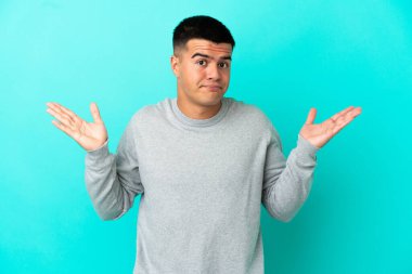 Soyutlanmış mavi arka planda genç yakışıklı adam şüpheli hareketler yapıyor.