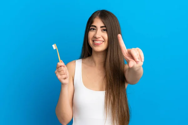 Młoda Kaukaska Kobieta Myje Zęby Odizolowane Niebieskim Tle Pokazując Podnosząc — Zdjęcie stockowe