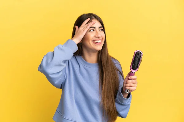 Joven Mujer Caucásica Sosteniendo Cepillo Aislado Sobre Fondo Azul Sonriendo —  Fotos de Stock