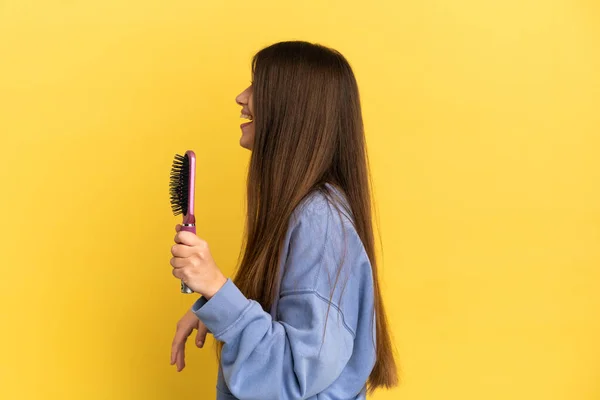 Joven Mujer Caucásica Sosteniendo Cepillo Aislado Sobre Fondo Azul Riendo —  Fotos de Stock