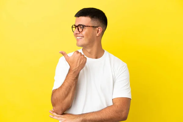 Mladý Pohledný Muž Přes Izolované Žluté Pozadí Ukazuje Stranu Prezentovat — Stock fotografie