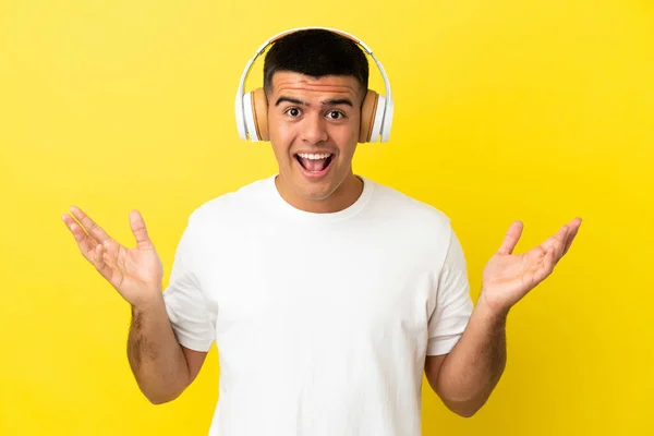 Jonge Knappe Man Geïsoleerde Gele Achtergrond Verrast Luisterend Muziek — Stockfoto