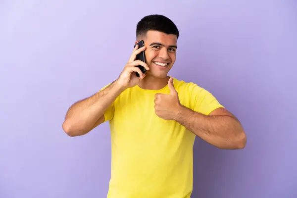 Молодий Красивий Чоловік Використовує Мобільний Телефон Над Ізольованим Фіолетовим Тлом — стокове фото