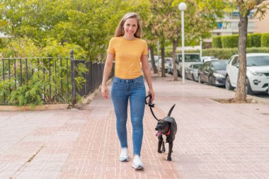 Dışarıda sevimli siyah köpeği olan genç sarışın kadın.