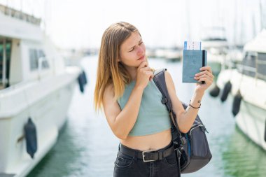 Pasaportu elinde tutan genç sarışın kadın üzgün bir ifadeyle.