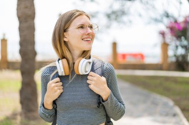 Genç sarışın kadın açık havada mutlu bir ifade sergiliyor.