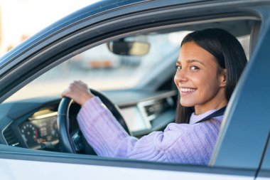 Genç bir kadın dışarıda, arabanın içinde.