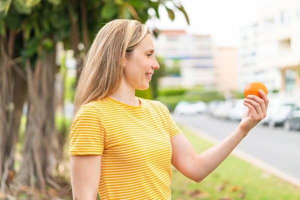 Açık Havada Elinde Portakal Tutan Genç Sarışın Kadın Mutlu Bir — Stok fotoğraf