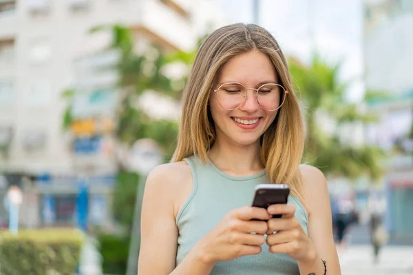 Молодая Блондинка Очках Улице Отправляет Сообщение Мобильного Телефона — стоковое фото