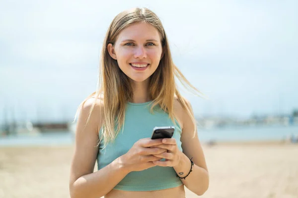 stock image Young blonde woman at outdoors sending a message with the mobile