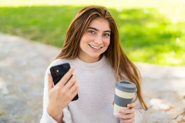 Giovane Bella Donna Caucasica Utilizzando Telefono Cellulare Tenendo Caffè Asporto — Foto Stock
